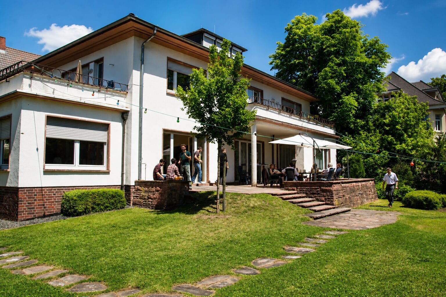 Das Nibelungenhaus mit Garten bei Sonnenschein, Bundesbrüder auf der Terrasse